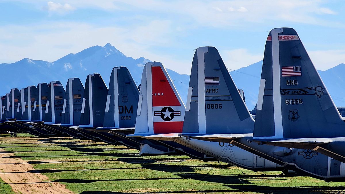 Colorful tail fins of retired airliners in a row with mountains behind