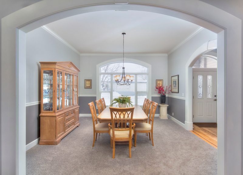 Dining room under an arched opening with a wood table and china cabinet