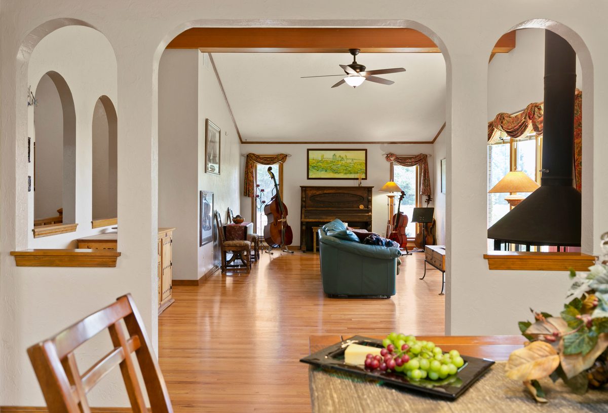Living room seen through arched doorways, with hardwood floors and a fireplace