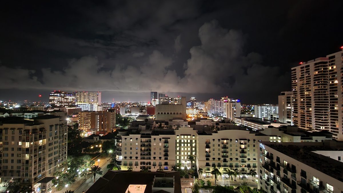 A city skyline at night under low dark clouds from a rooftop