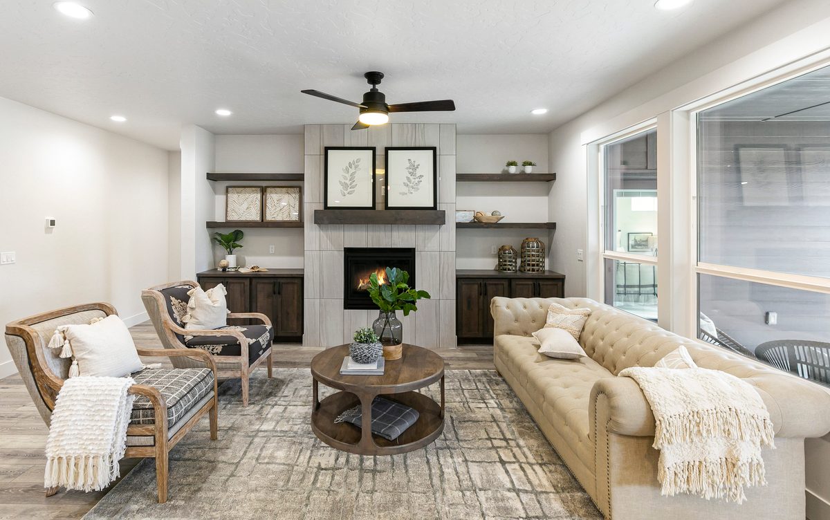Living room with a cream sofa, built-in shelves, a fireplace and tall windows
