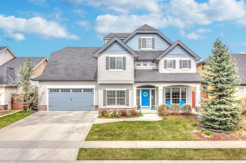 Two-story craftsman-style home with a gray garage door and landscaped front yard