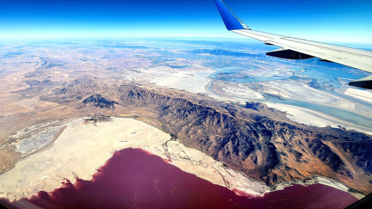 A desert landscape and dry lakebed seen from an airplane window