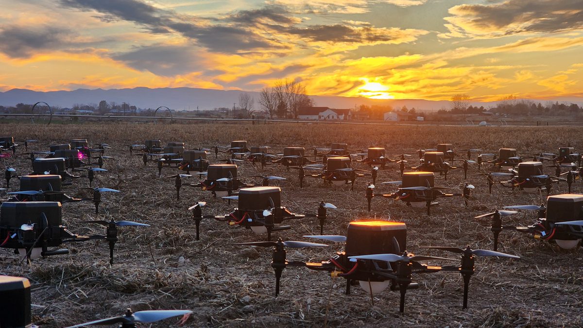 Hundreds of drones waiting on a field under a golden sunset