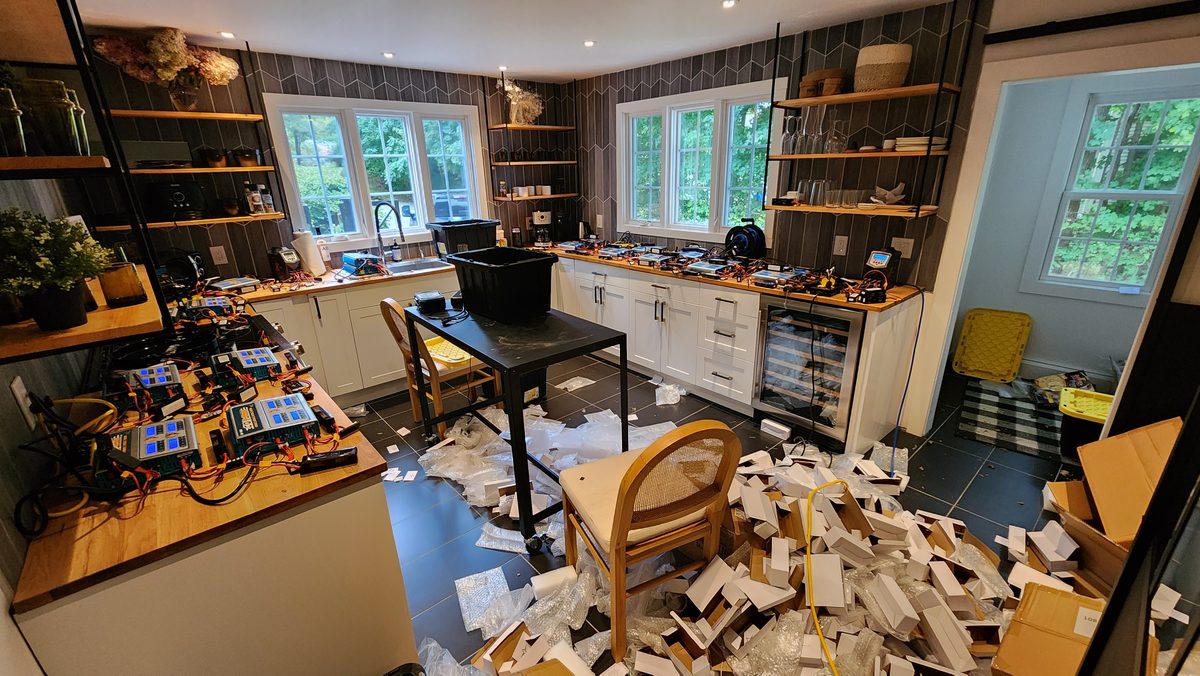 A cluttered workstation with monitors, laptops and drone gear