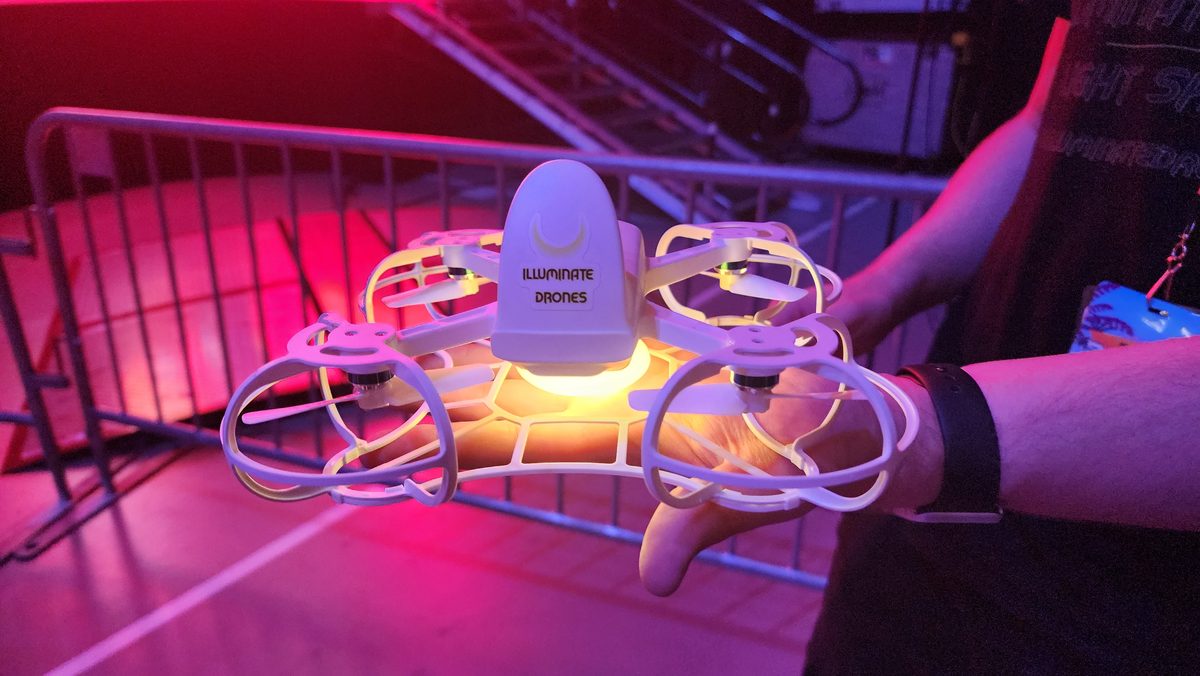 A small drone glowing under pink and red light on a workbench