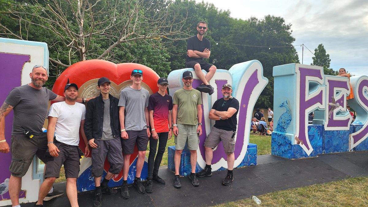 A drone show crew posing in front of giant festival letters