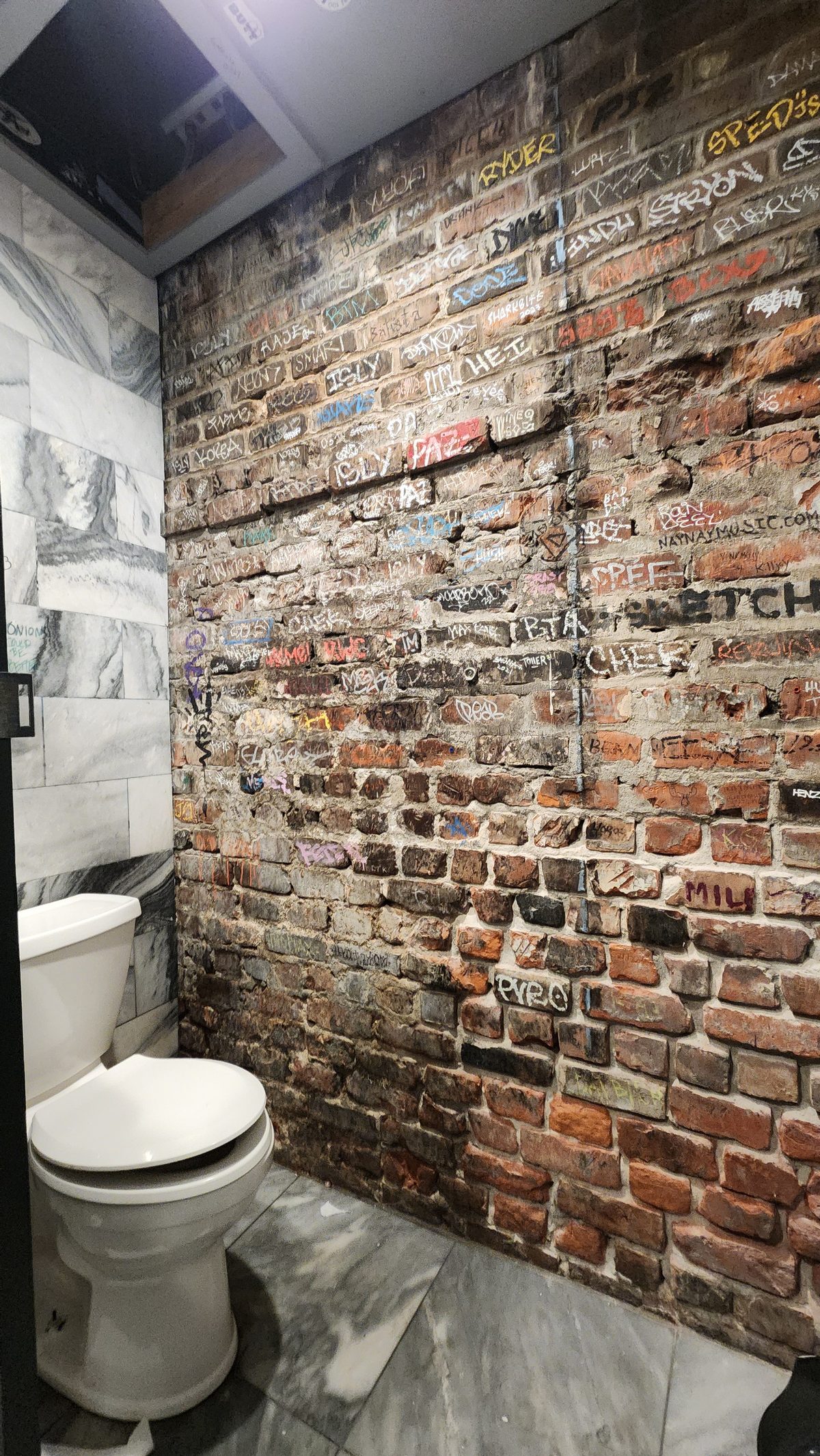 A small restroom with a rough exposed-brick wall