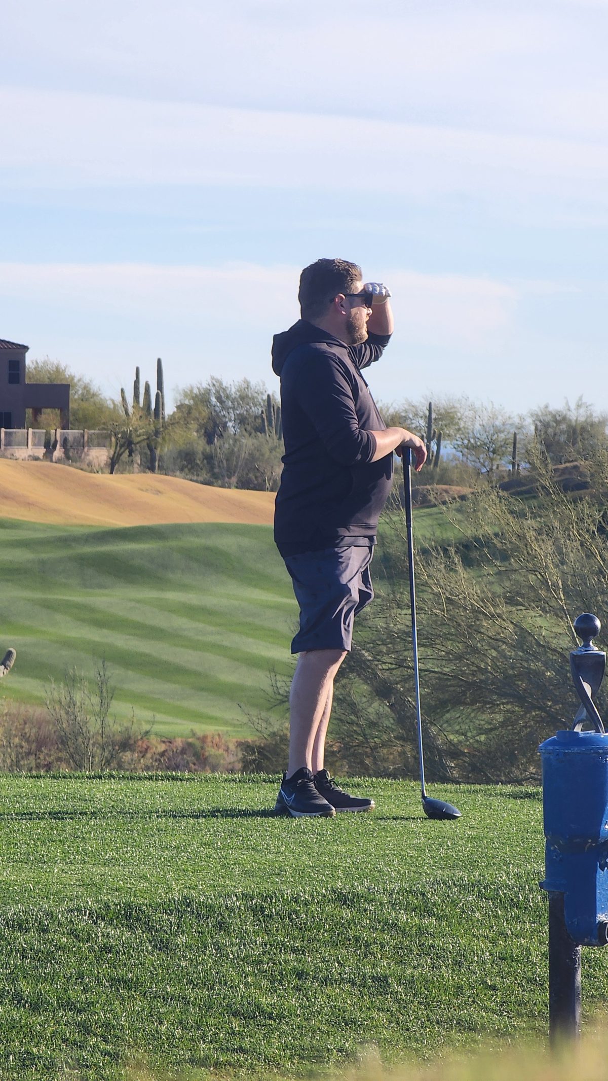A golfer in a cap lining up a putt on a desert course