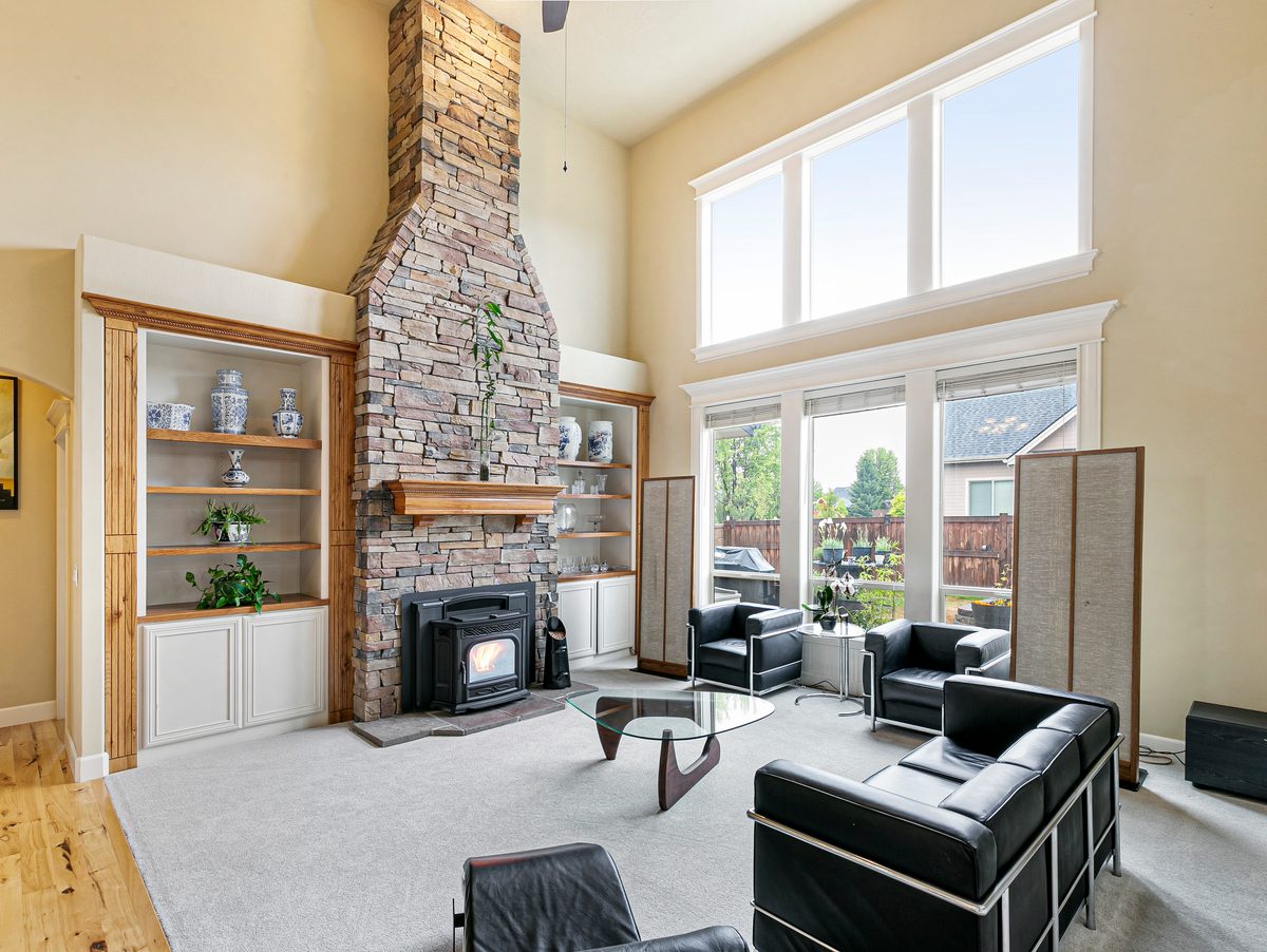 Great room with a two-story stacked-stone fireplace, built-in shelves and tall windows