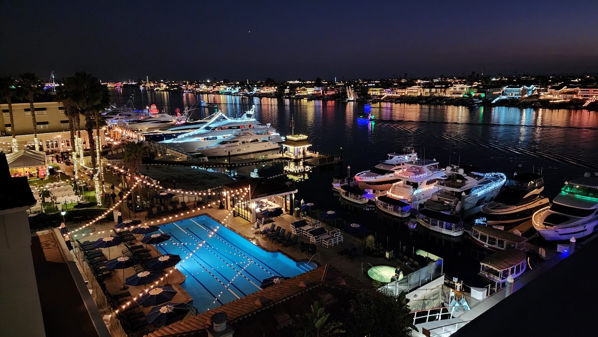 Yachts and harbor homes lit up along the water at night