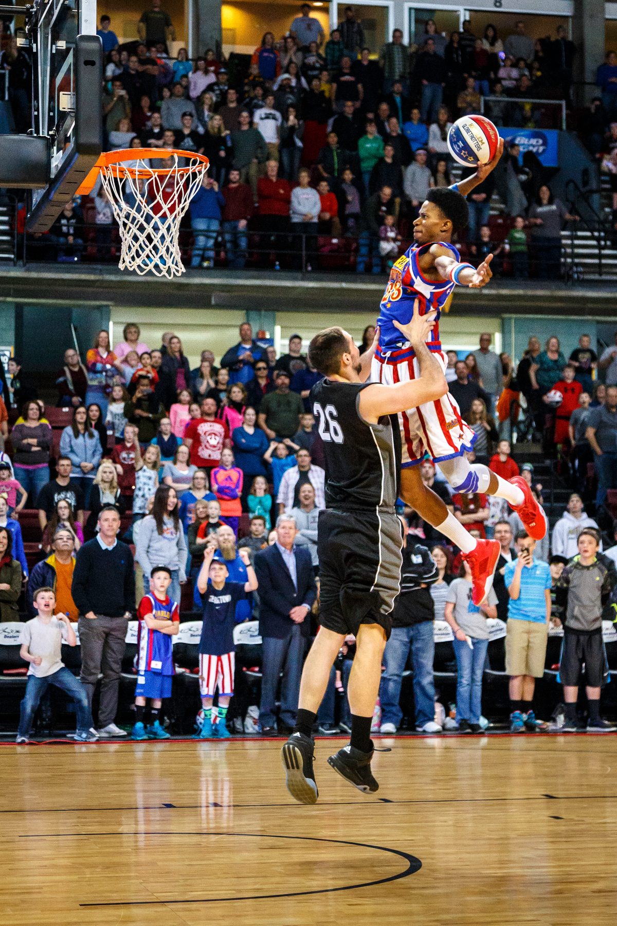 A Harlem Globetrotters player soaring for a dunk in front of a packed arena crowd