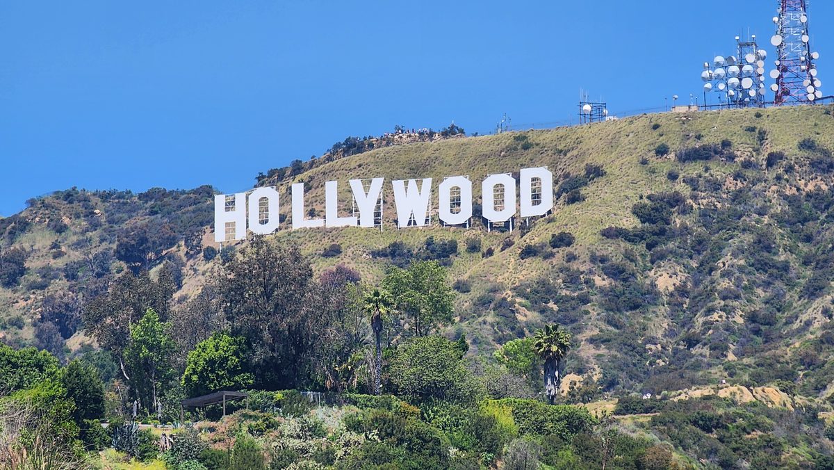 The Hollywood Sign on a green hillside under a blue sky