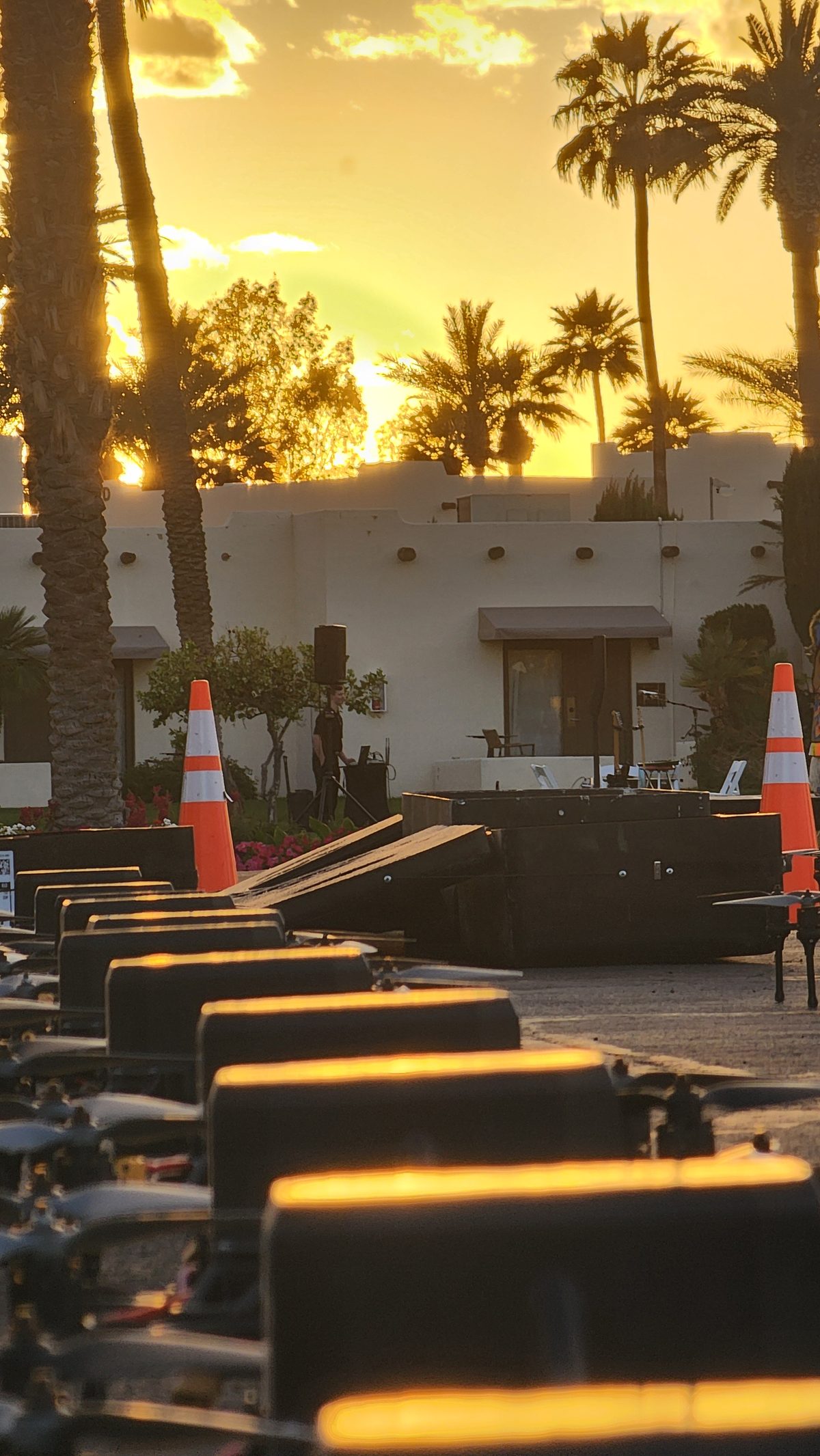 Lit steps leading toward palm trees and a golden sunset