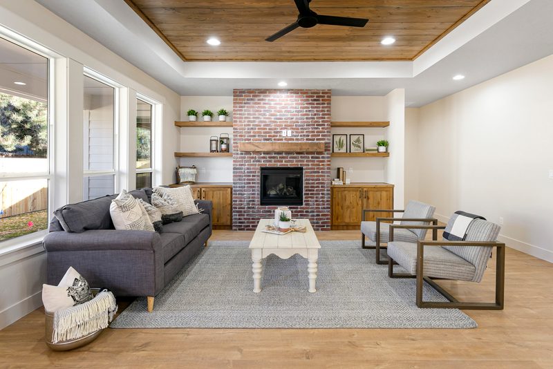 Living room with a brick fireplace, built-in shelves and a tongue-and-groove wood ceiling