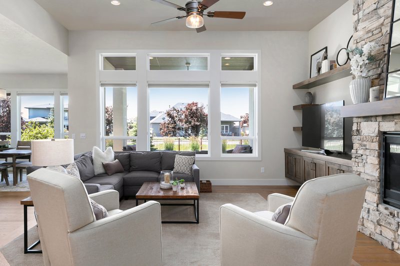 Living room with white armchairs, a stone fireplace and large picture windows