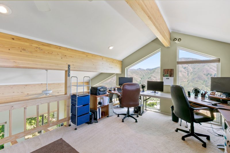 Upstairs loft office with desks under a vaulted wood-beam ceiling