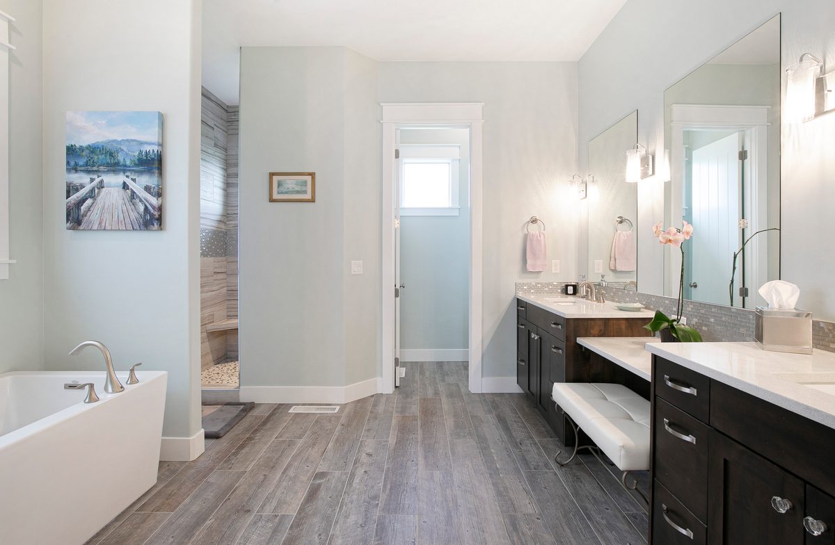 Modern bathroom with a freestanding tub, makeup vanity and plank floors
