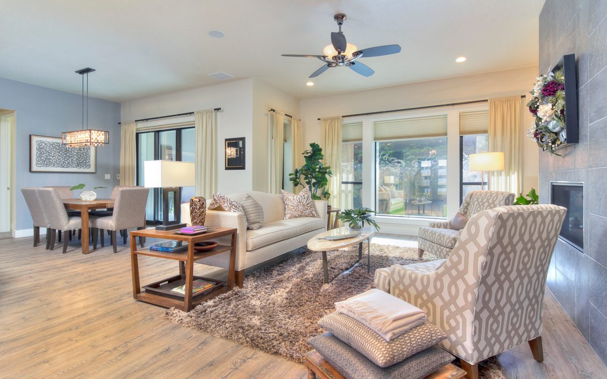 Open living and dining area with a ceiling fan and soft natural light