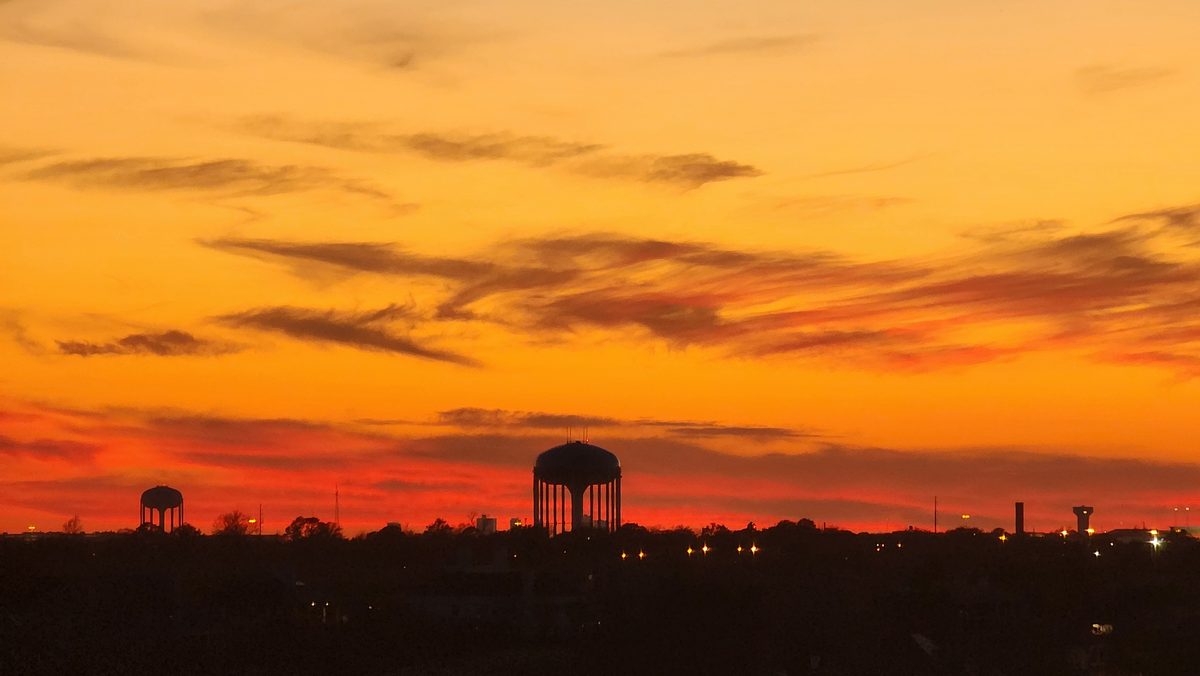 A blazing orange sunset over a low skyline and water tower