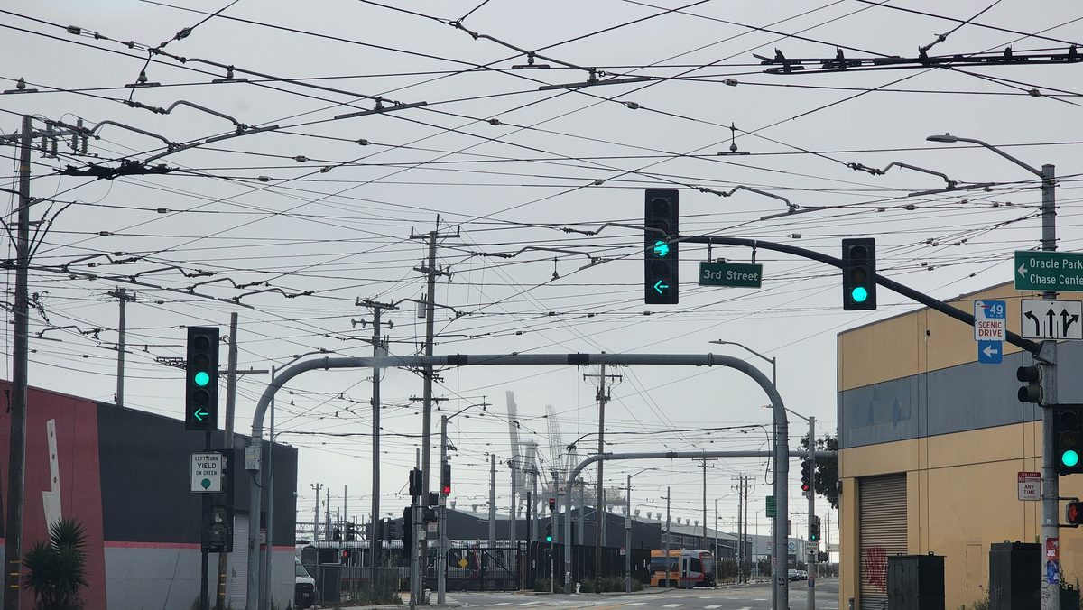 A city intersection under a web of overhead power and trolley wires