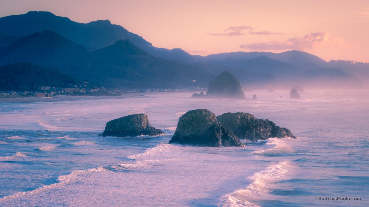 Waves washing around sea stacks under pink pastel light on a misty Pacific coast