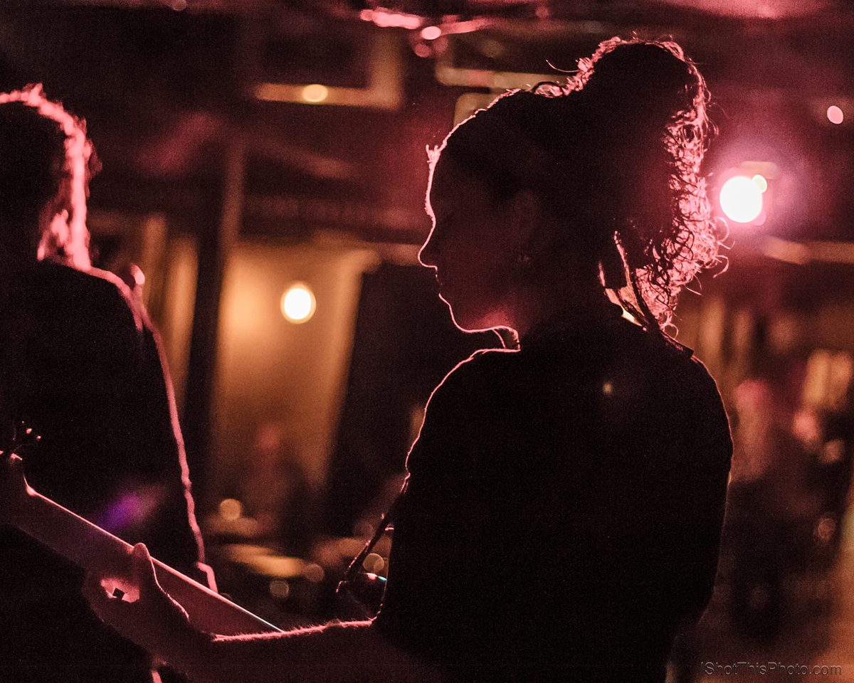Silhouettes of a singer and bassist washed in red stage light