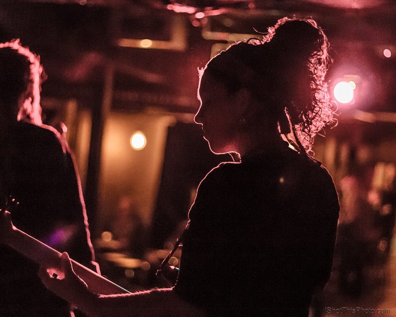 Silhouettes of a singer and bassist washed in red stage light
