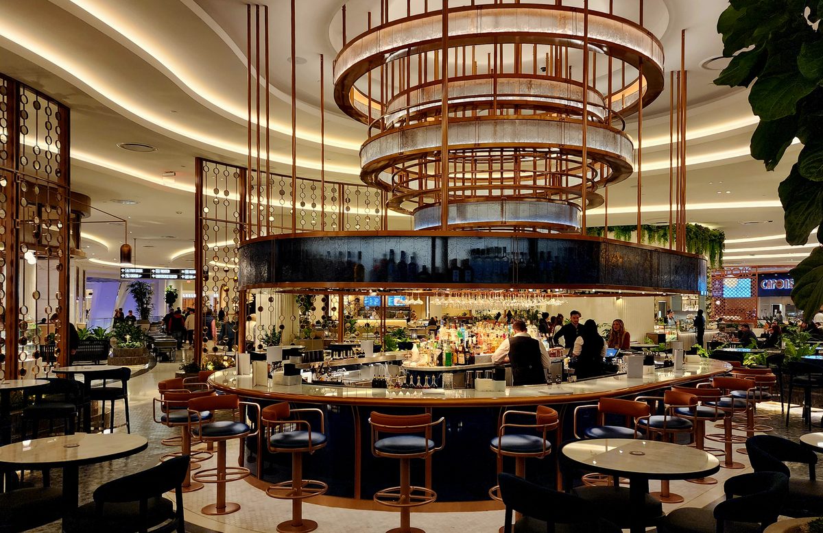 A circular bar beneath a golden ring chandelier in a resort