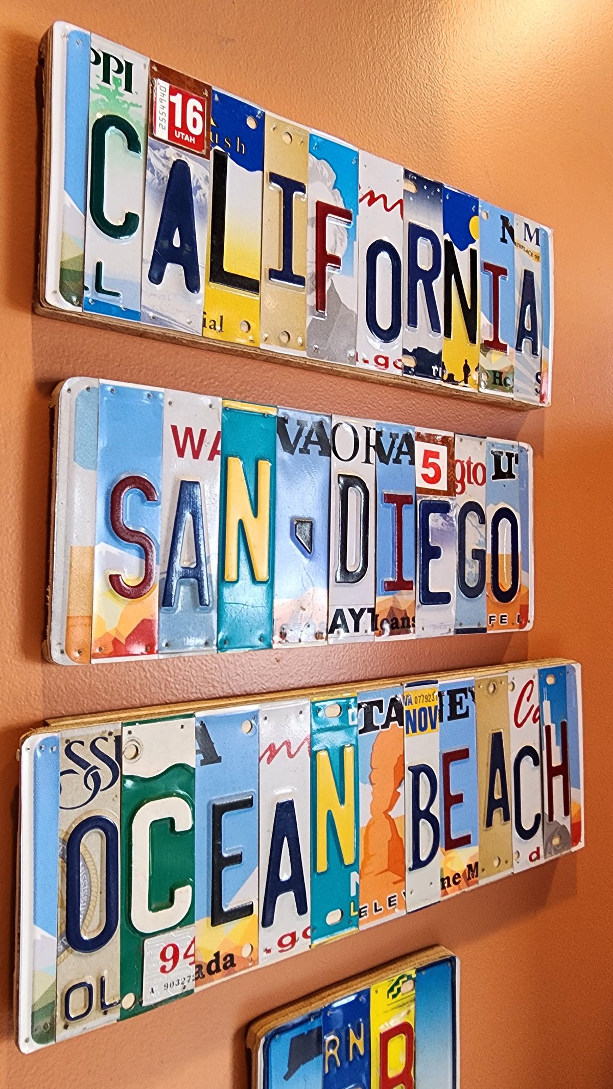 A wall sign spelling California, San Diego and Ocean Beach in old license plates