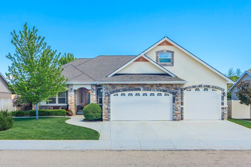 Front exterior of a single-level home with a three-car garage under a blue sky