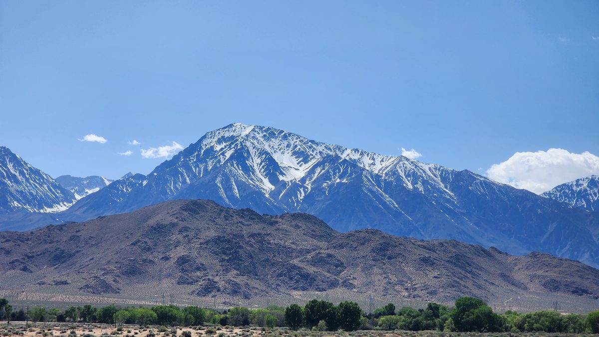Snow-capped mountains above a green valley under a blue sky
