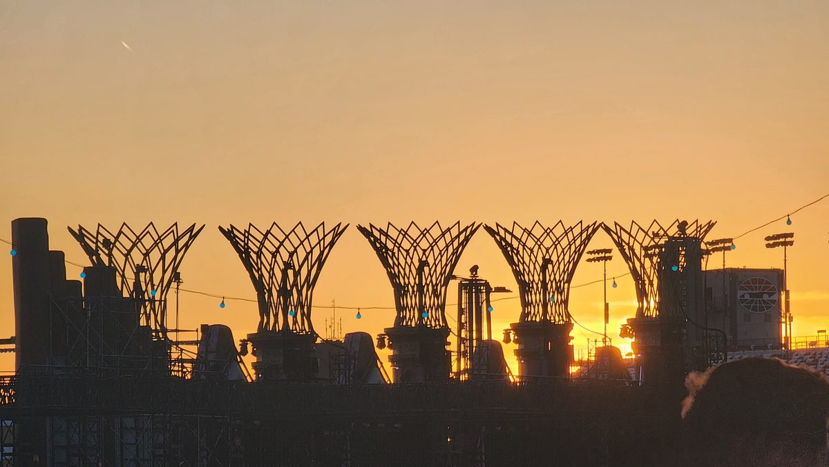 A row of steel arches silhouetted against a soft sunset