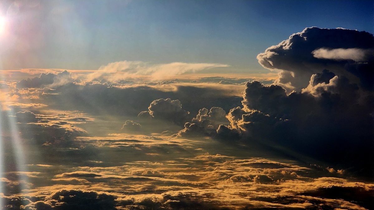 Golden sunlight breaking through towering clouds seen from an airplane