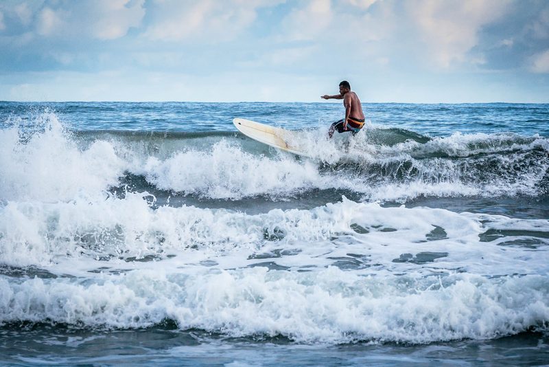 A surfer carving across a breaking wave under a blue sky in Costa Rica
