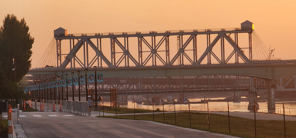 A steel truss bridge and river under a hazy orange sunset