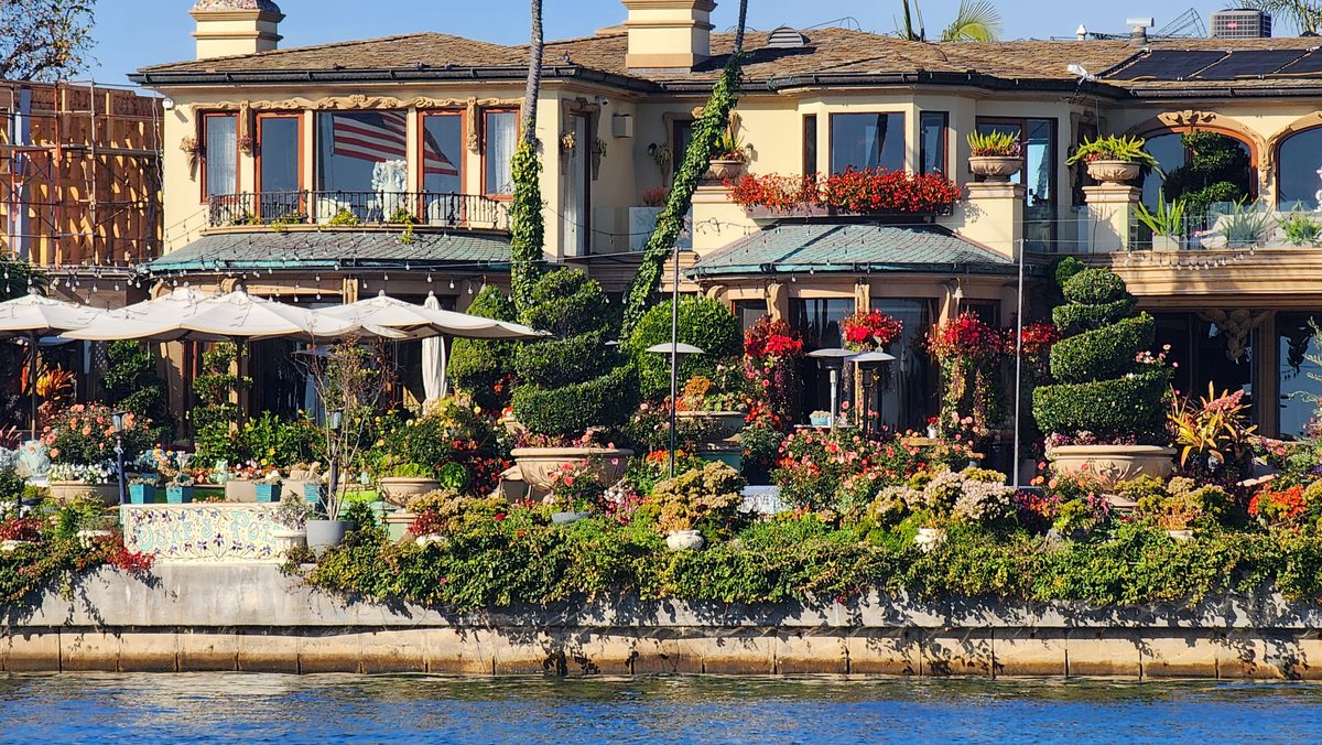 Mediterranean-style waterfront villas with lush gardens along a harbor