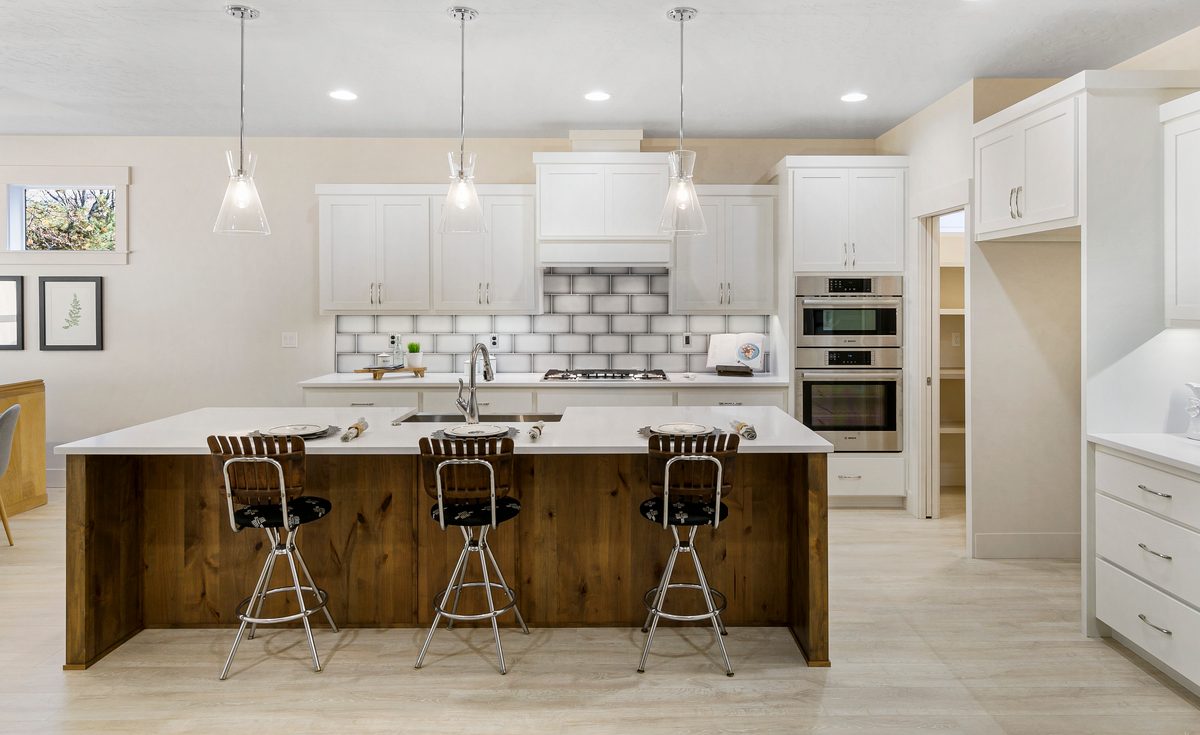 White kitchen with a subway tile backsplash, pendant lights and a wood-paneled island
