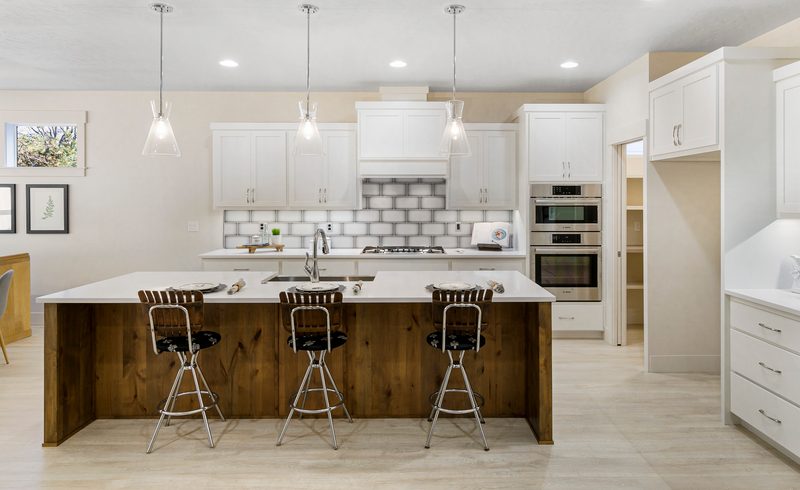 White kitchen with a subway tile backsplash, pendant lights and a wood-paneled island