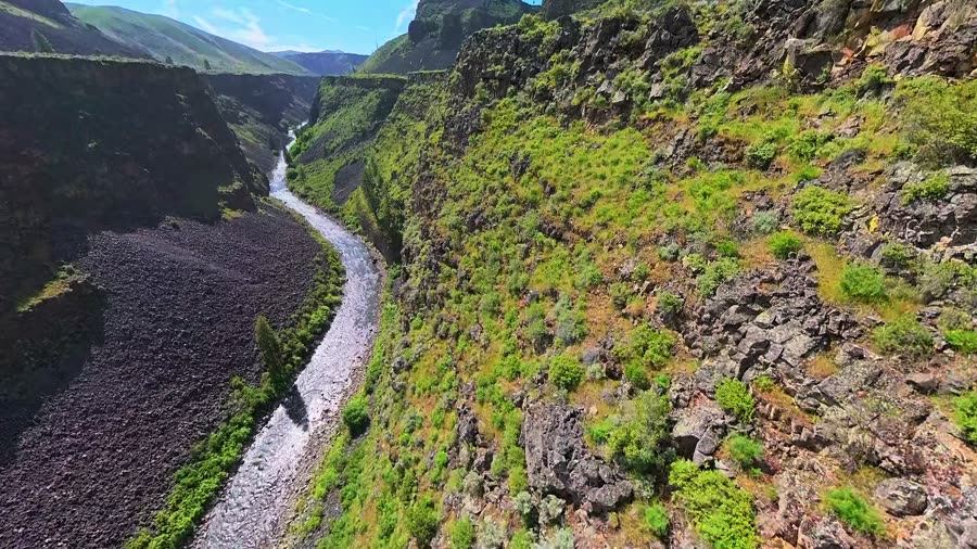 FPV drone dives down a basalt river canyon