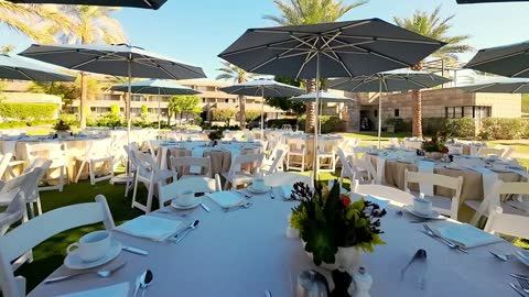 FPV flythrough over set dinner tables under umbrellas at a resort